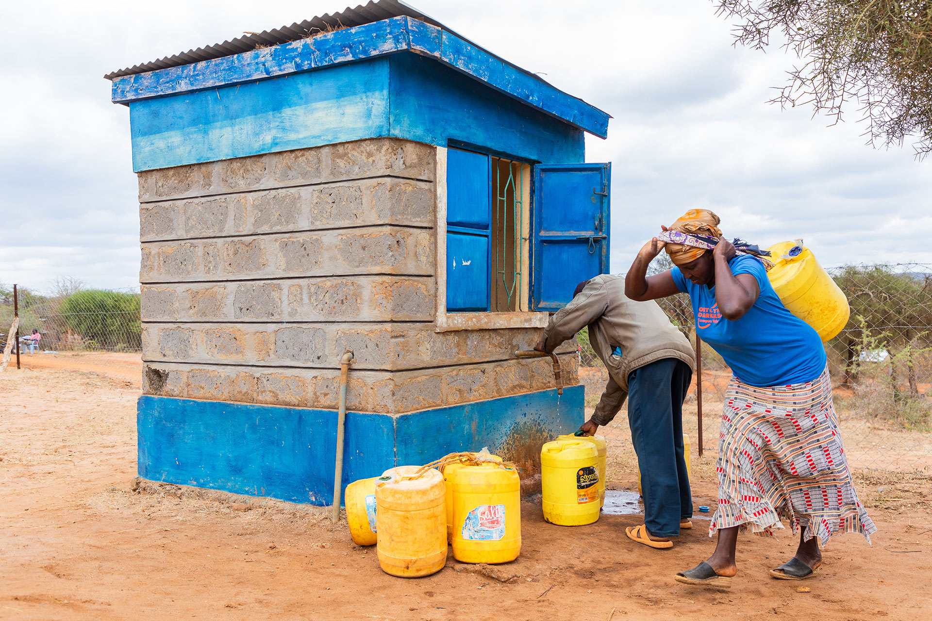 A woman carries water on her back at Kwekuyu water kiosk, Kitui County